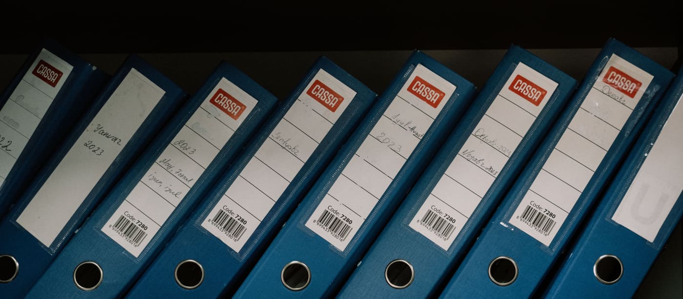 A shelf of office binders with dated labels along their spines.
