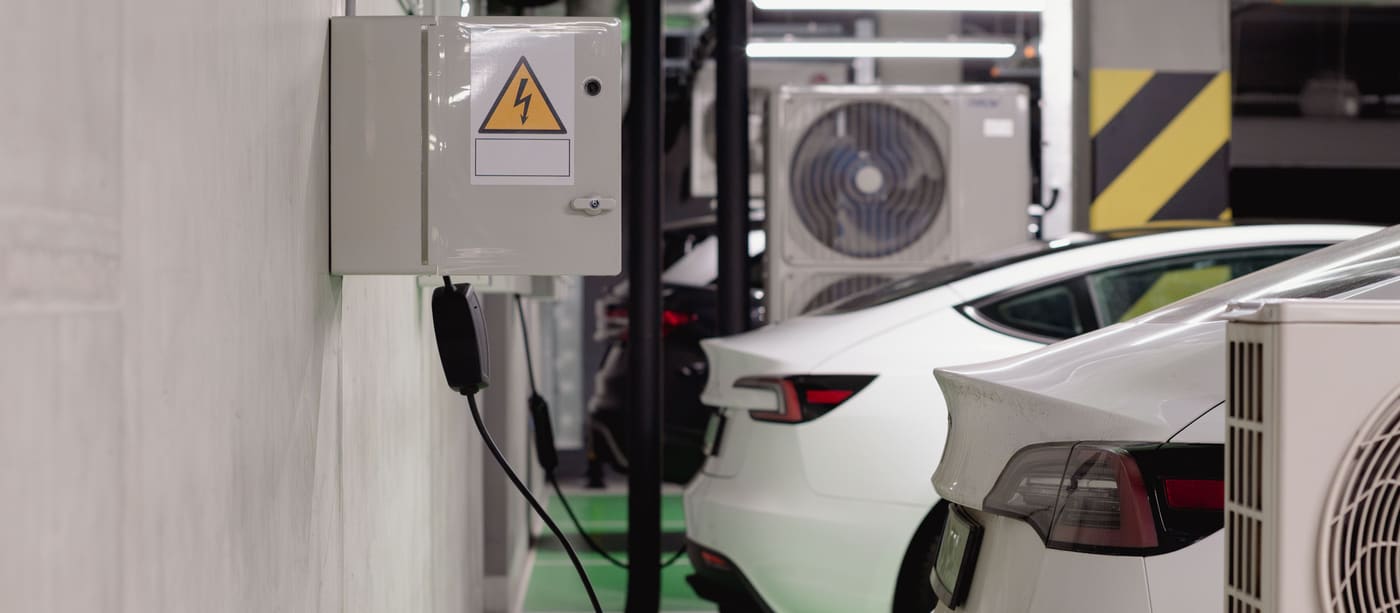 Electric cars plugged into charging points in an underground car park.