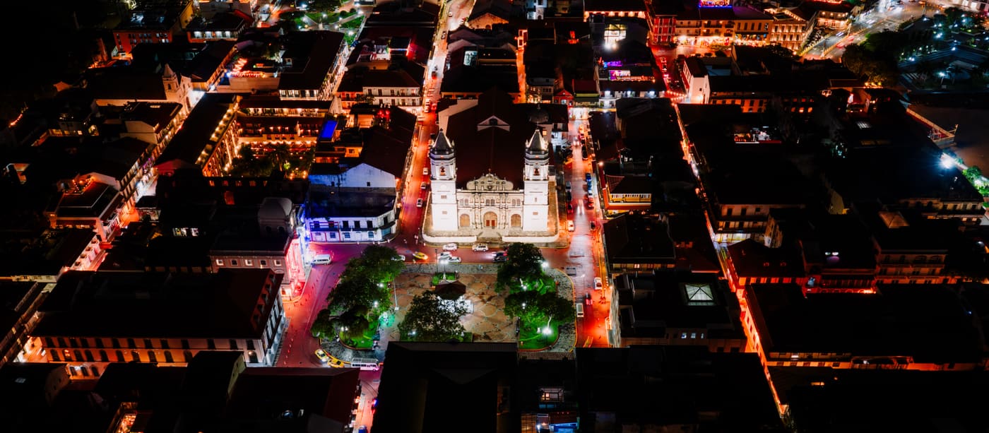 Aerial view of a Latin American city centre at night, streets picked out in light.