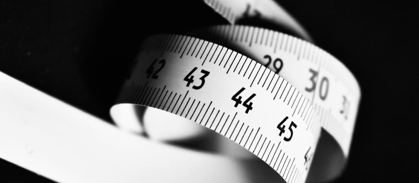 A white measuring tape curving across a dark background, showing the numbers 15 to 45.