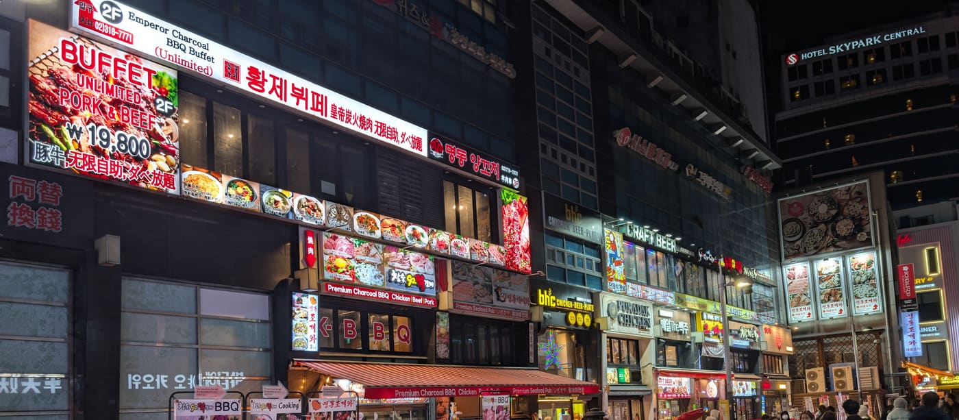 A Seoul street lined with restaurants, their Korean signs stacked up the building fronts.