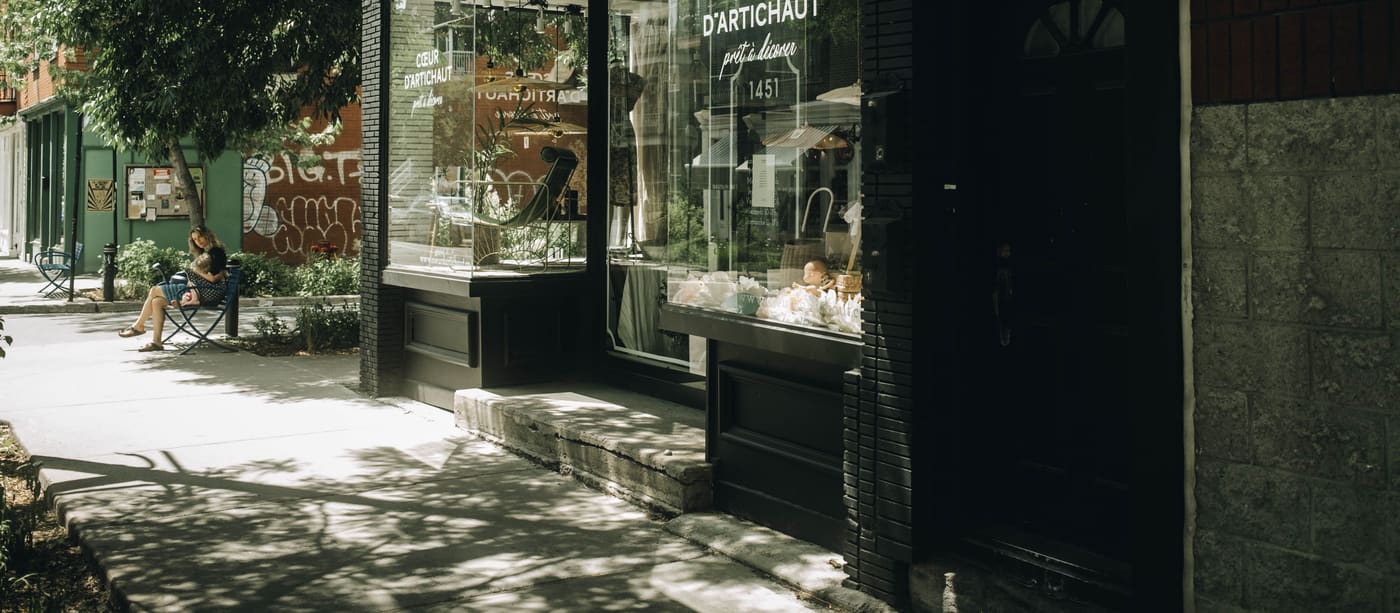 The glass shopfront of a small independent business on a sunlit street.